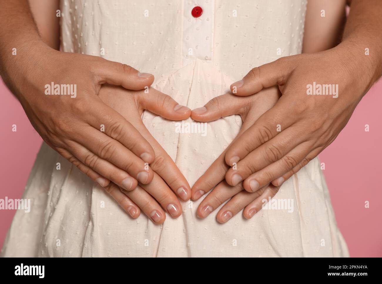 Man hugging his pregnant wife on pink background, closeup Stock Photo ...