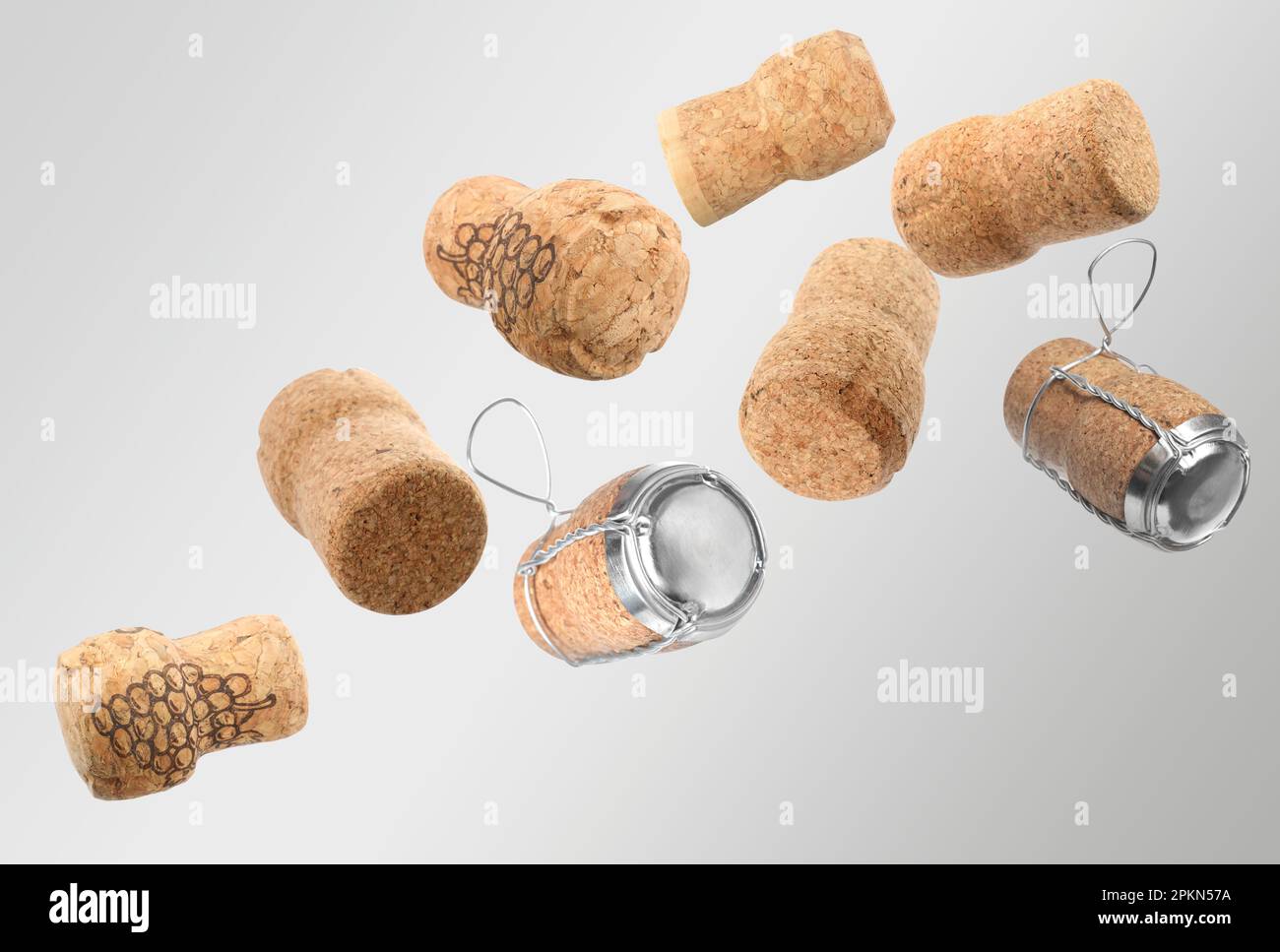 Many corks of sparkling wine bottles falling on light grey background