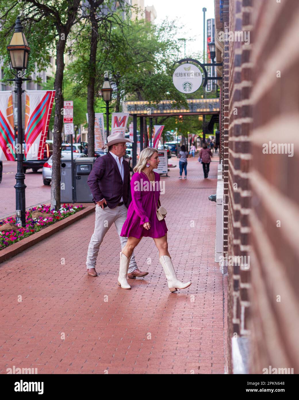 This local couple is dressed in typical Fort Worth style, wearing white hats and boots with purple clothing as a nod to the city's Western heritage. T Stock Photo