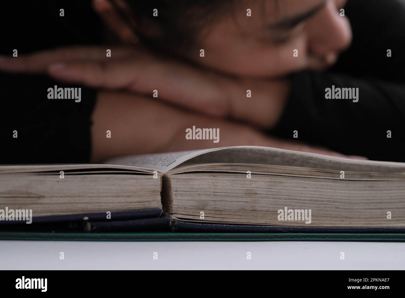 Tired young woman lying on a book after hard work Stock Photo - Alamy