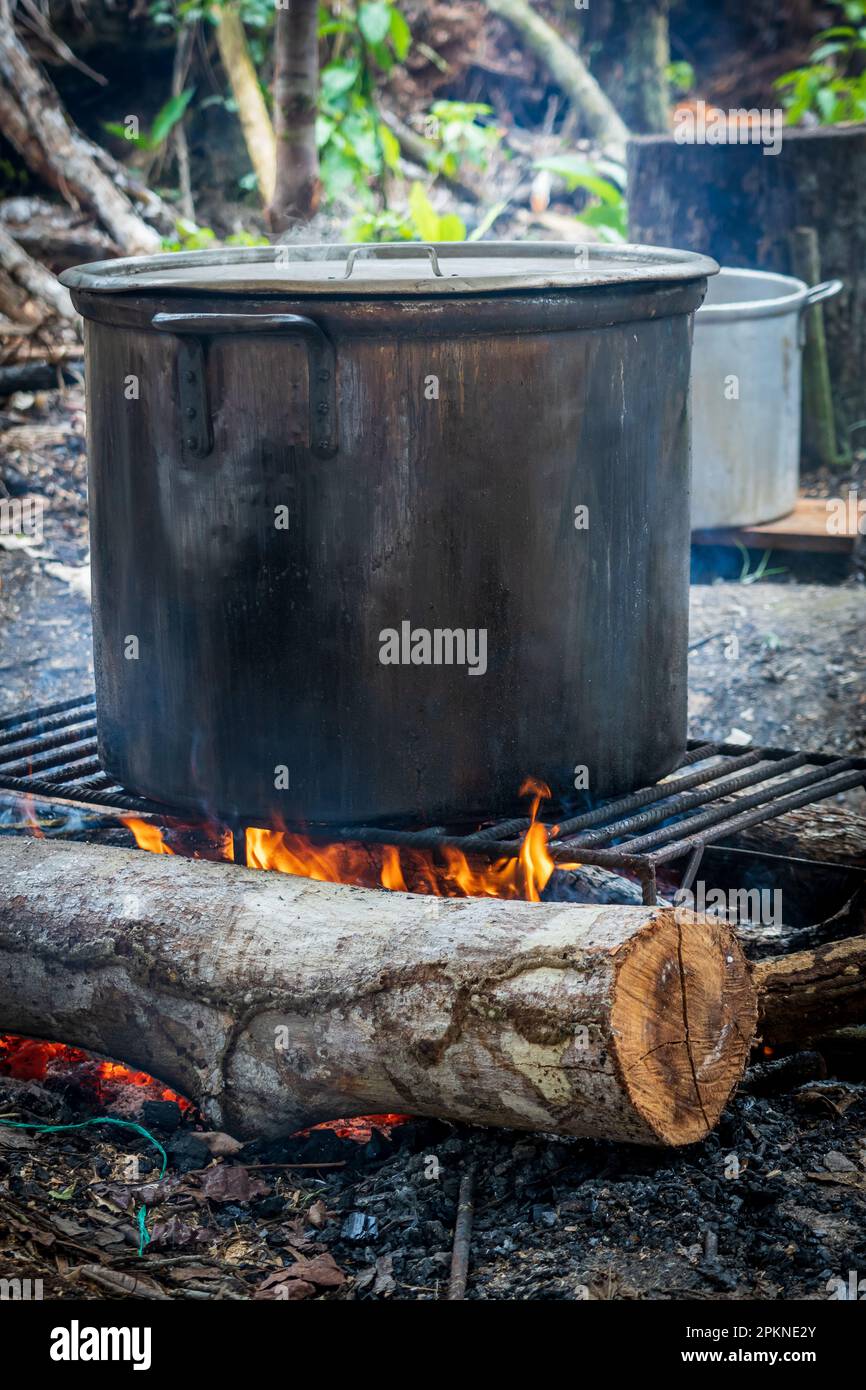 A fire burns and distills a black kettle of ayahuasca in Peru Stock Photo