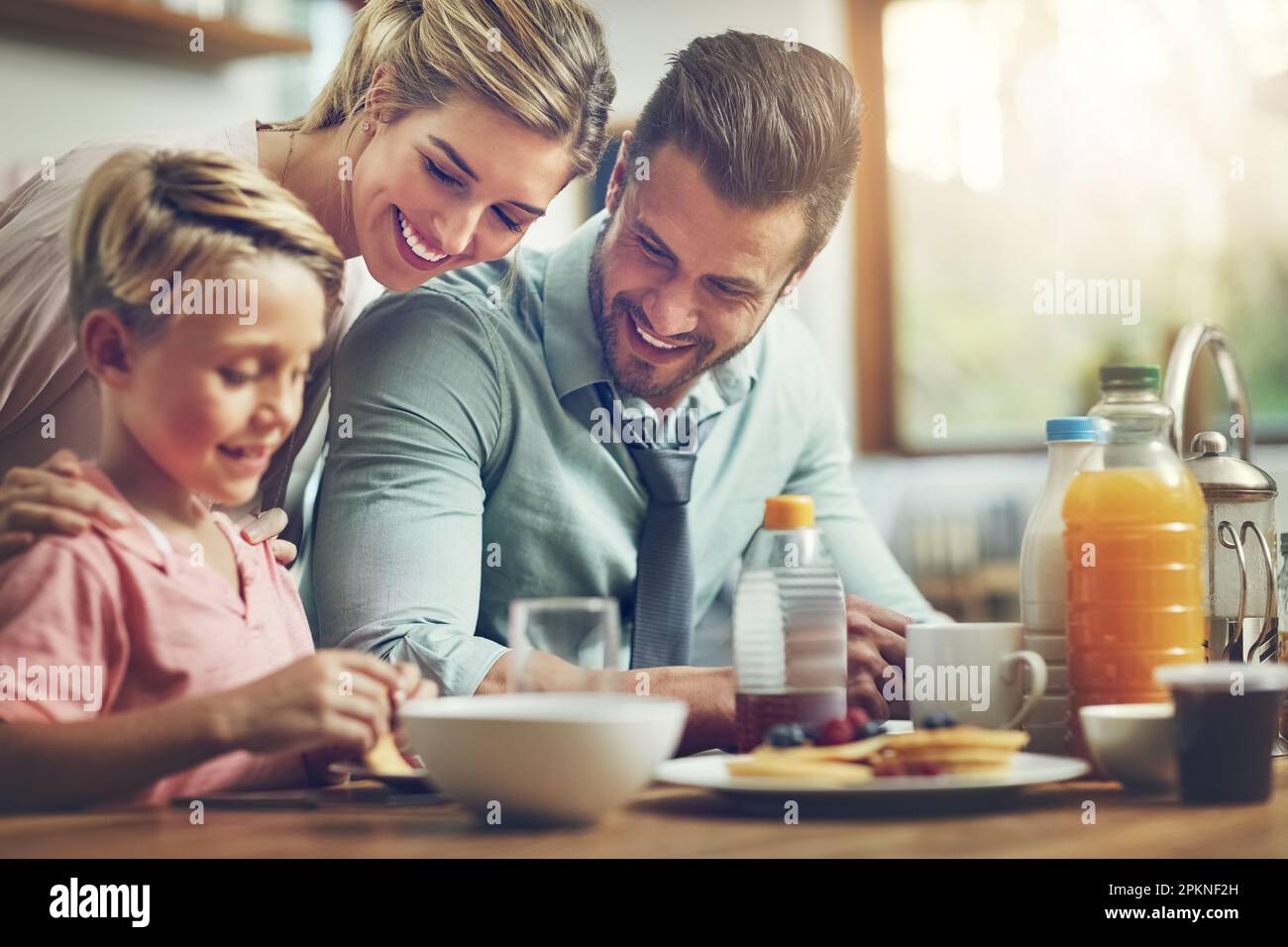 He brings joy to our hearts. a little boy eating breakfast with his parents. Stock Photo