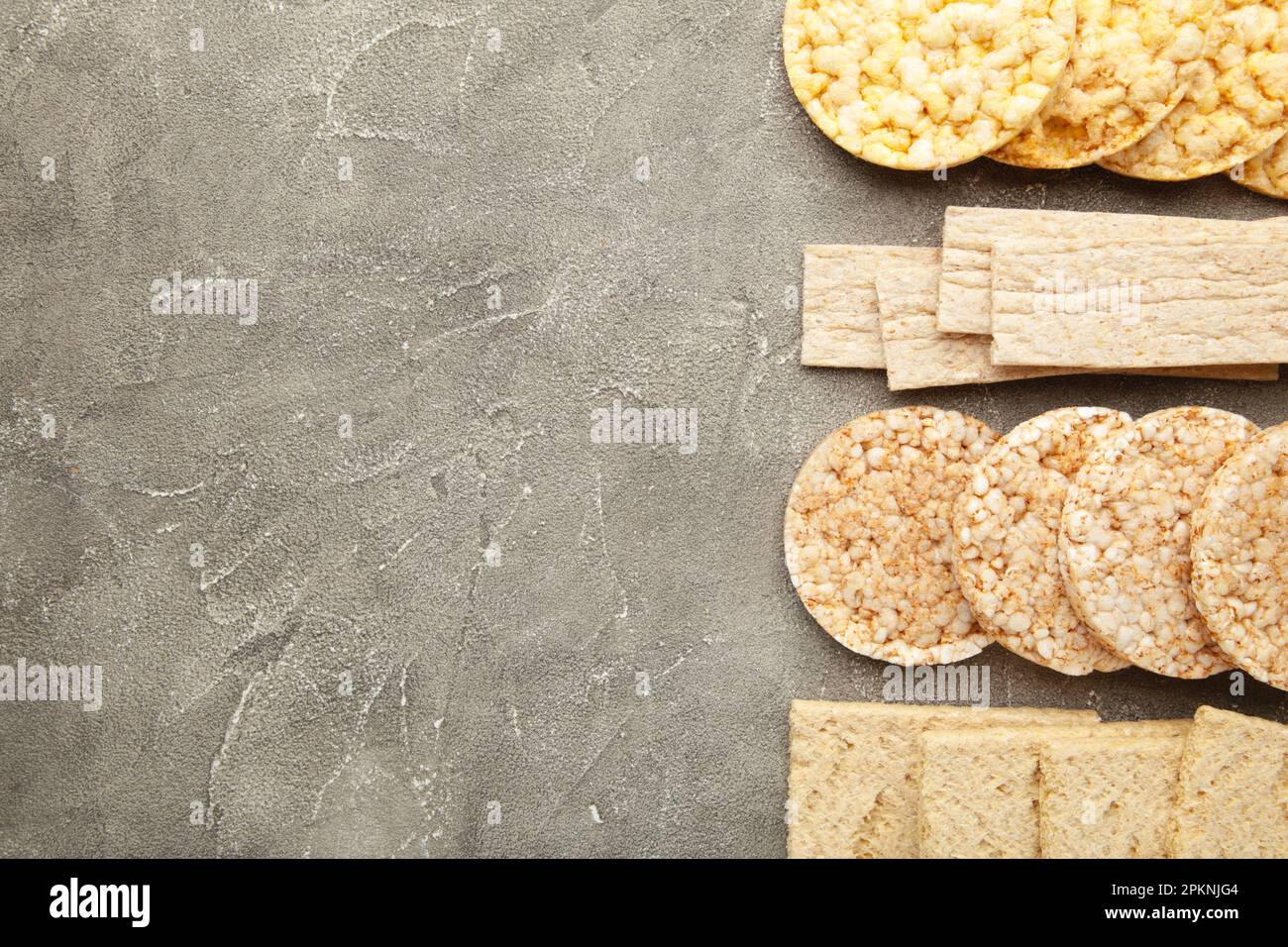 Various types of healthy whole grain crispbreads on grey background ...