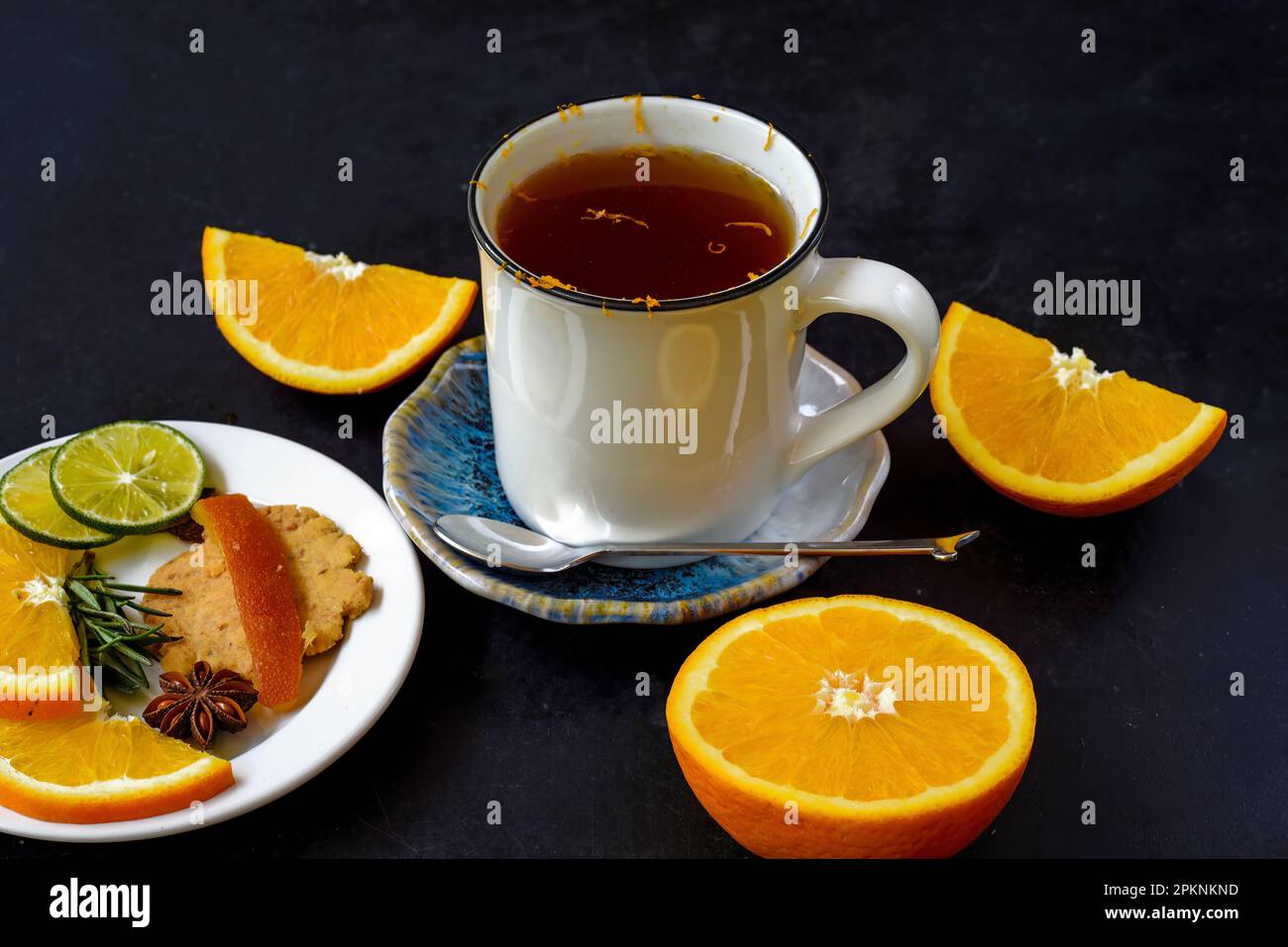 Orange cinnamon tea with crystalized fruits and cookies on black bacground Stock Photo