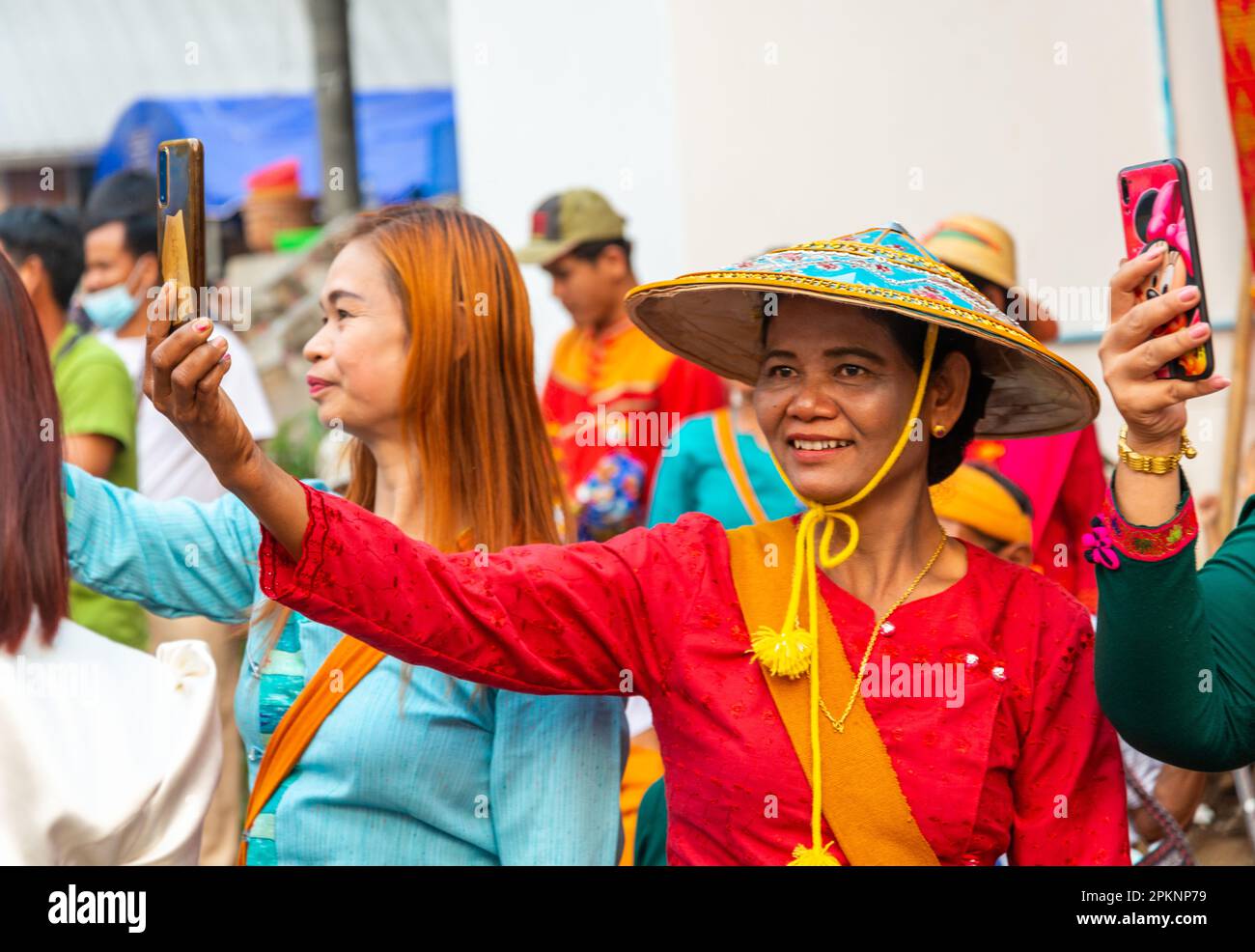 Pai,Northern Thailand-April 4th 2023:Women take pictures of the passing street procession,attended by hundreds of Thais,where boys are ordained to be Stock Photo