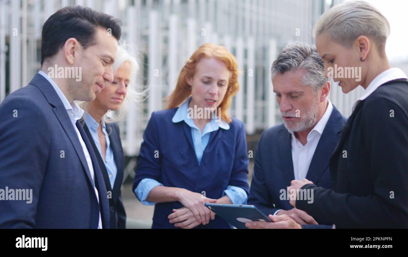 Businessman dividing tasks among his employees while using a tablet Stock Photo