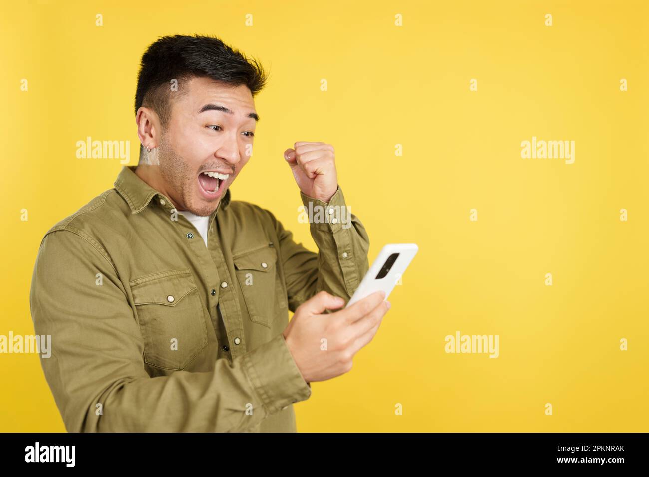 Excited chinese man celebrating while using the mobile phone Stock Photo