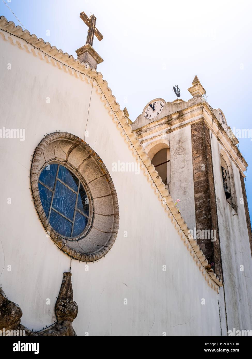 Low angle view of the facade of Parish Church Monchique, Igreja de Nossa Senhora da Conceição, backlit by the sun with a clock reading almost twelve. Stock Photo