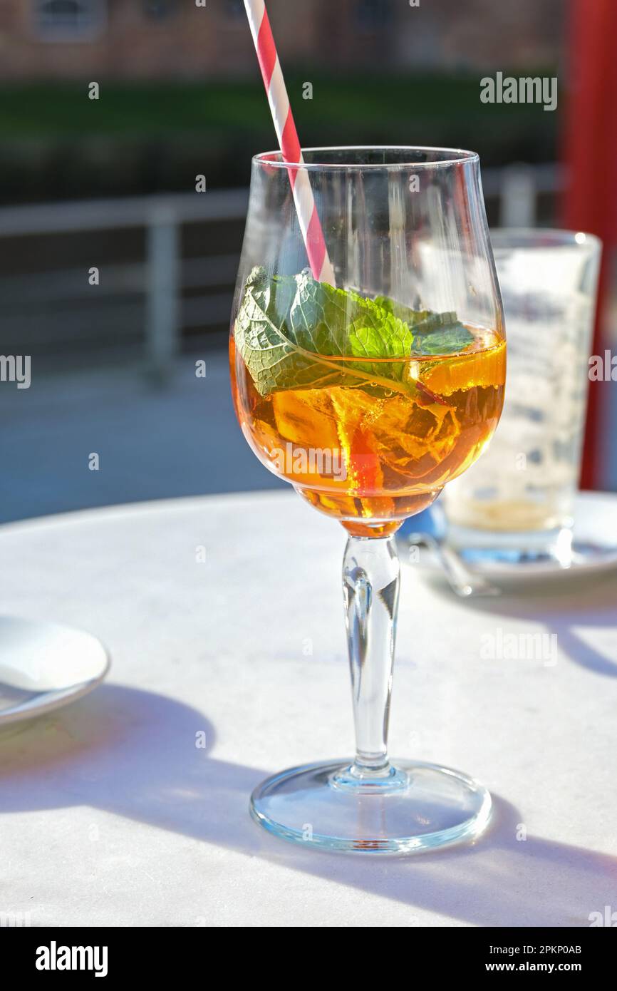 Aperol spritz drink with ice and mint leaves in a glass on a table in a city street cafe on a sunny day, copy space, selected focus, narrow depth of f Stock Photo