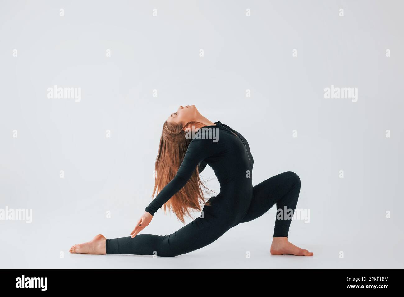 Side stretch. Young woman in sportive clothes doing gymnastics indoors ...