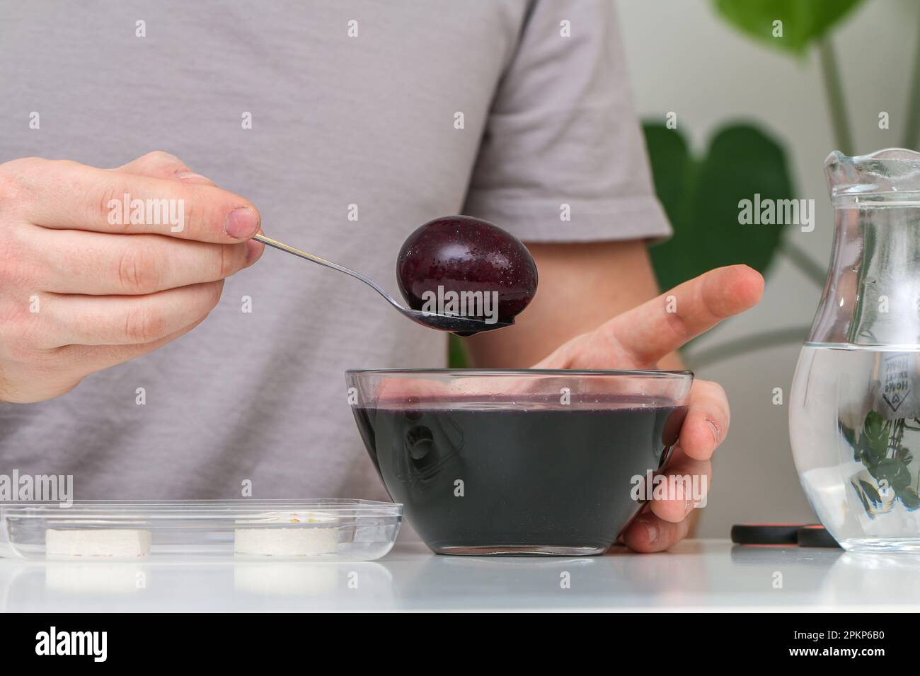 A man takes out colored Easter eggs from colored water. Dyeing easter eggs with food coloring is the first step in favorite Easter egg decorating idea Stock Photo