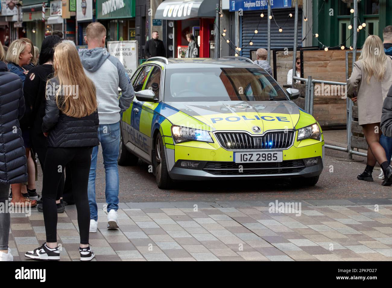 PSNI Police Service of Northern Ireland skoda patrol car with blue lights drives through busy pedestrian area on call out in Belfast City Centre, Nort Stock Photo