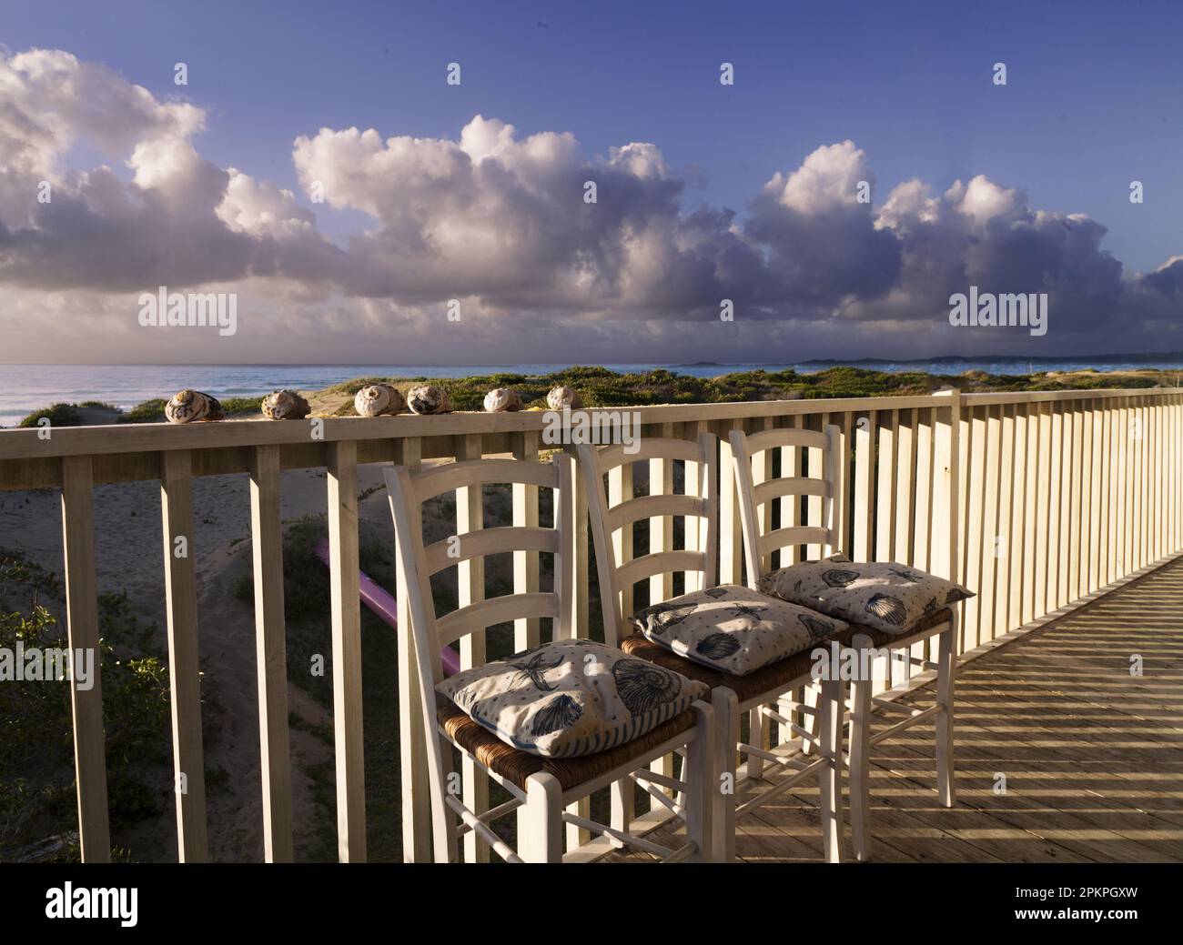 Tropical early morning clouds line the horizon at Stilbaai coastal village. This beach house and veranda lies on the sanddunes and the beach. Stock Photo