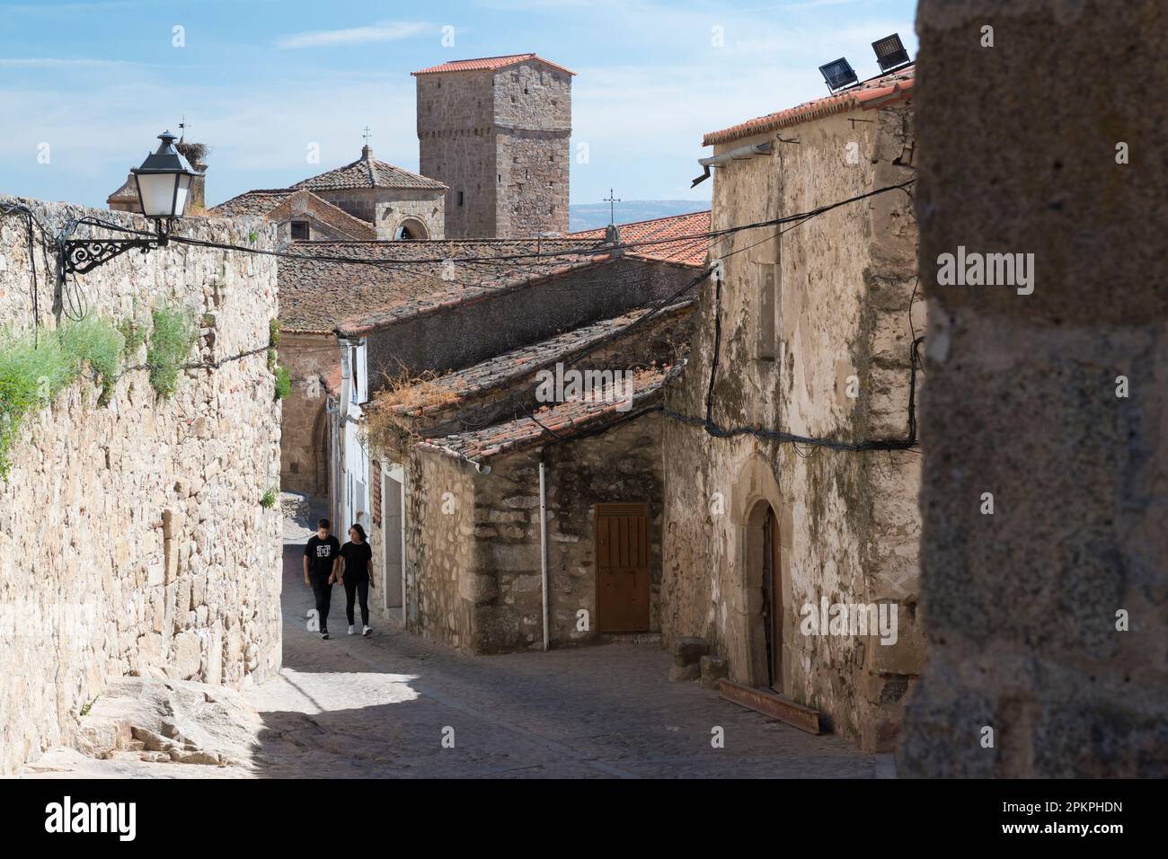 Young couple walking in an alley between stone houses in the historic part of Trujillo, Extremura, Spain. Stock Photo