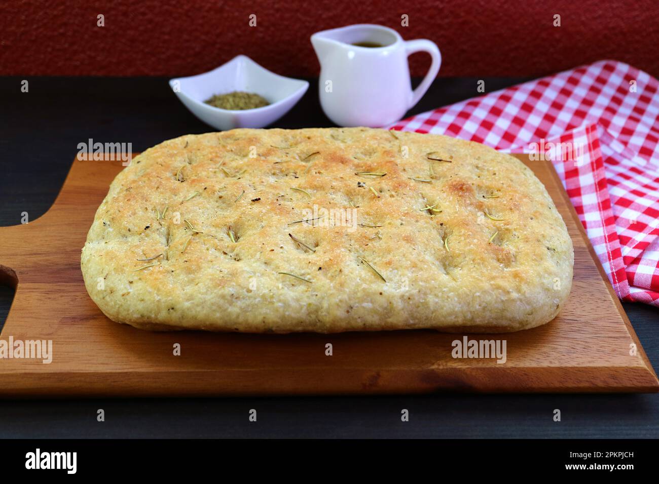 Delectable Freshly Baked Italian Herbed Focaccia Bread on Wooden Breadboard Stock Photo