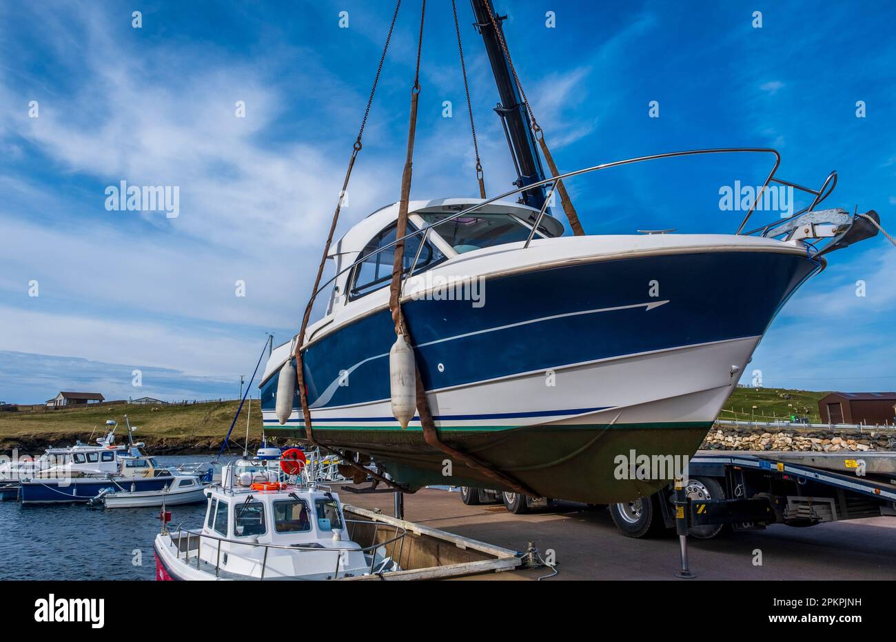 Lifting a small cabin cruiser from the water for repairs in the small harbour at Bridge End, West Burra, Shetland Isles, Scotland Stock Photo