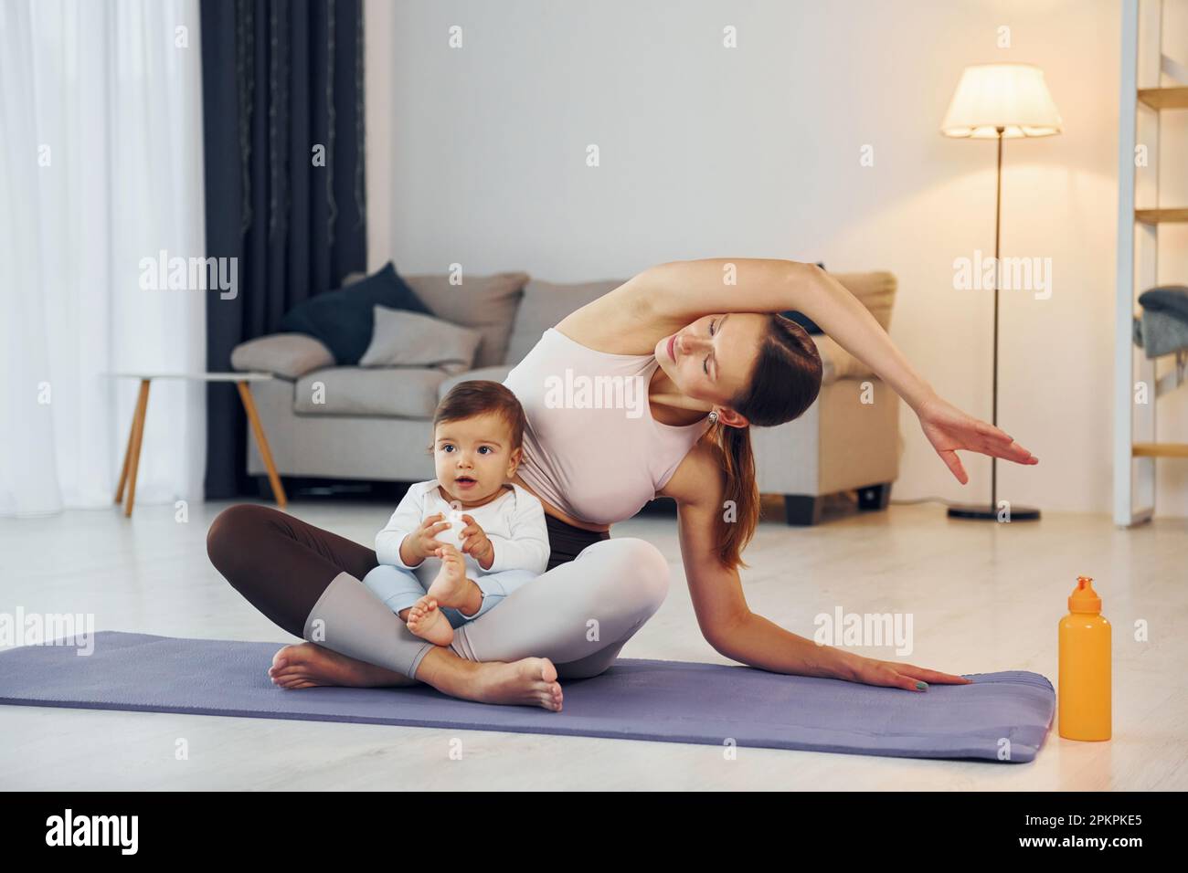 Doing yoga exercises. Mother with her little daughter is at home ...