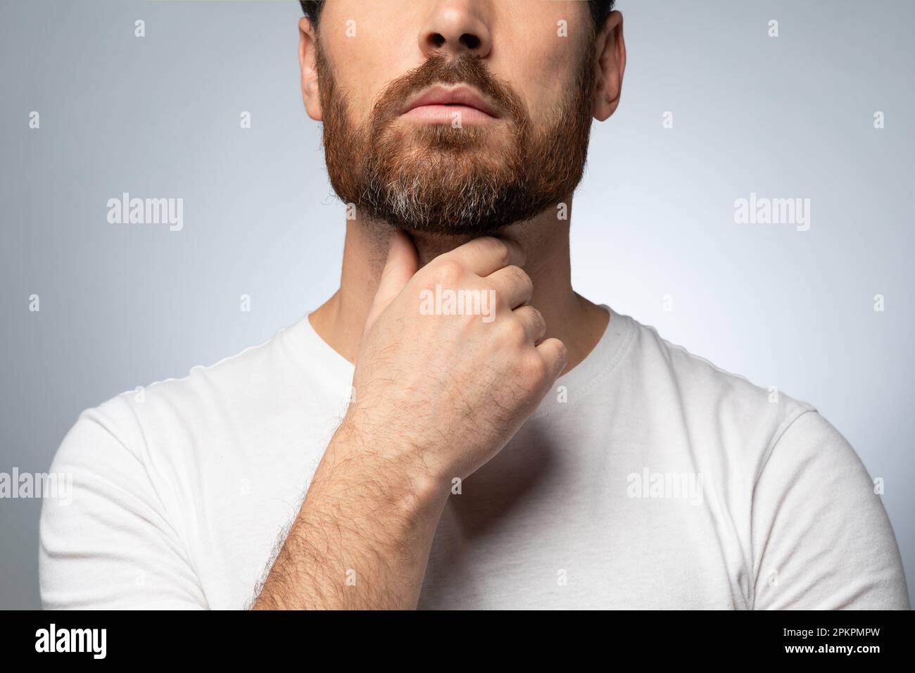 Unrecognizable bearded man touching painful neck, suffering from sore