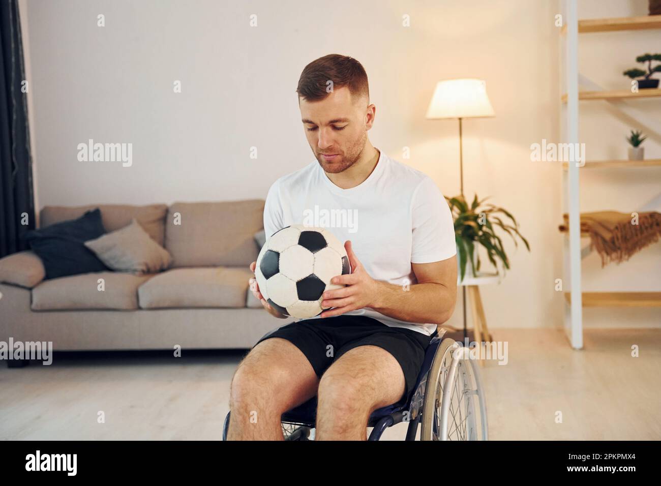 With soccer ball. Disabled man in wheelchair is at home Stock Photo Alamy