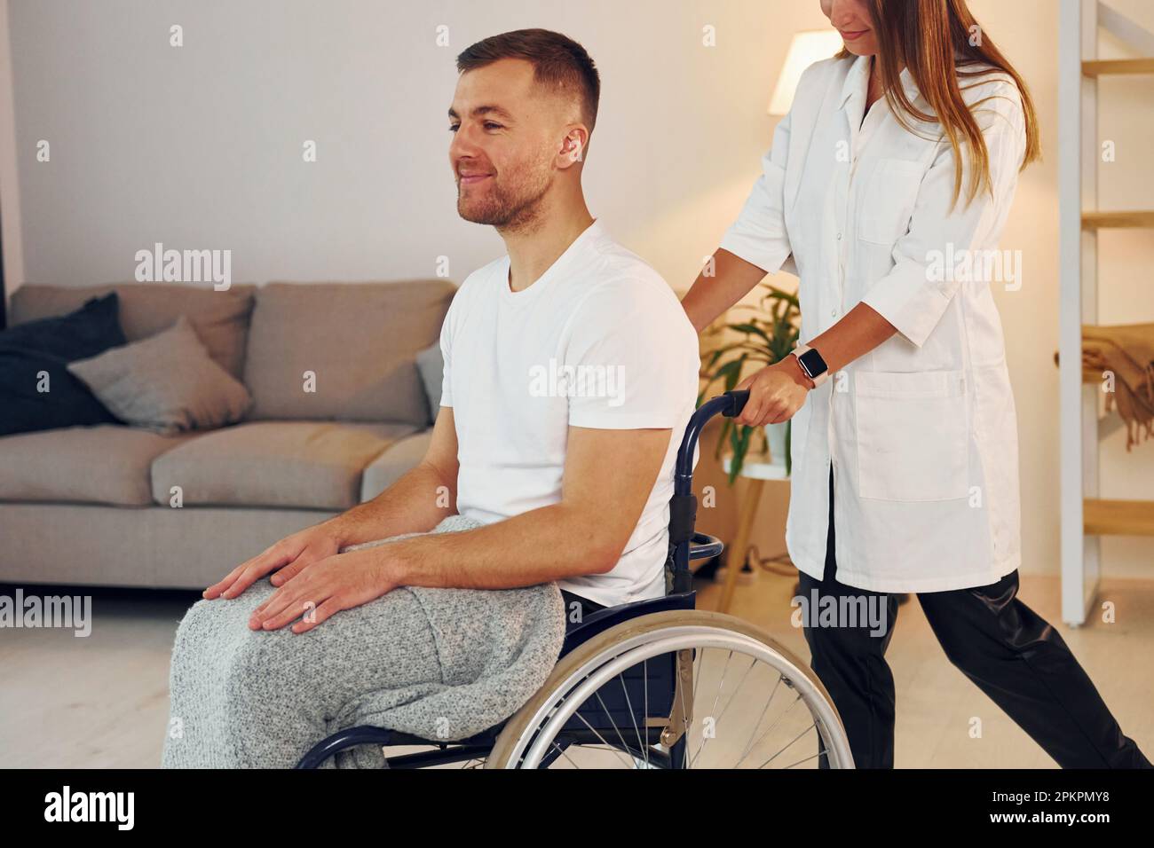 Woman is helping. Disabled man in wheelchair is at home Stock Photo - Alamy