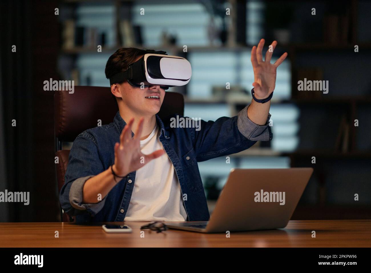 Young businessman using laptop and wireless VR headset at workplace Stock Photo
