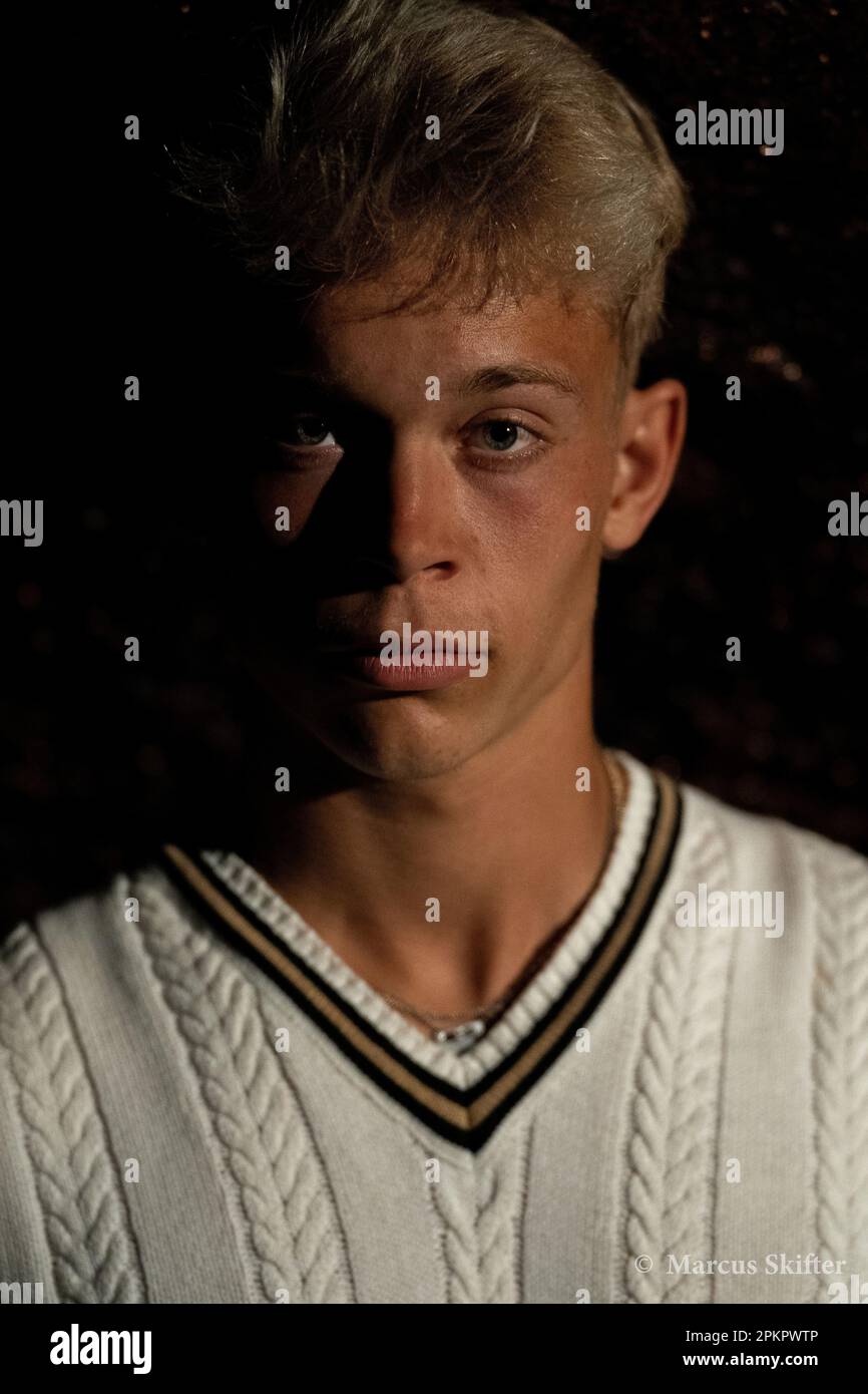 A man in a white sweater on a black background with emphasized facial ...