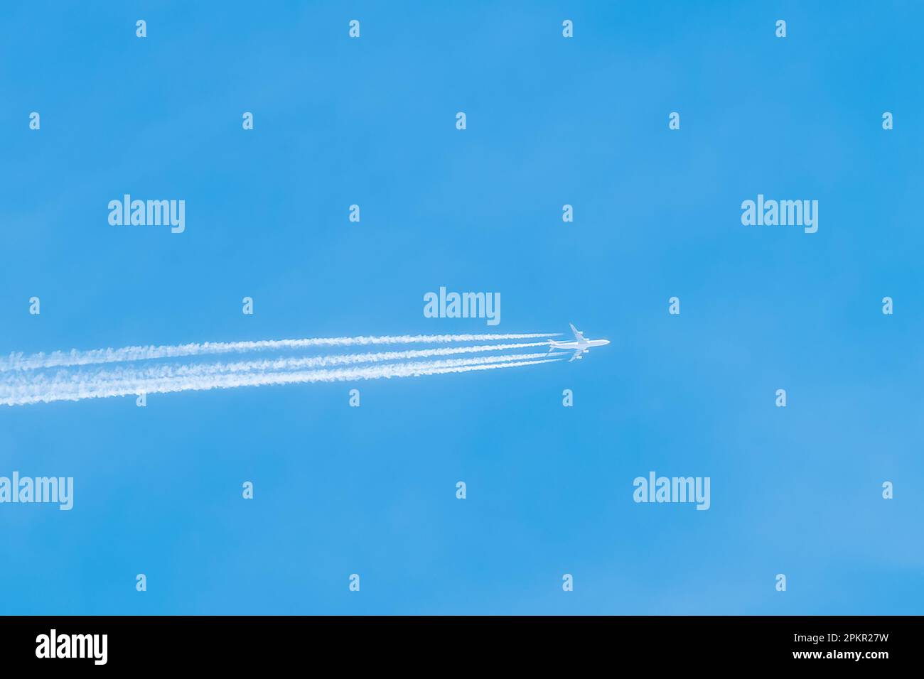 Shot of a jet plane high in the blue skies. Airliner in the blue sky leaves air trails. Travelling on airplanes. Stock Photo
