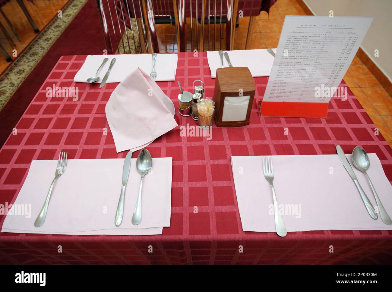 Table served for lunch in the dining room of restaurant: spoons, forks, knives. Stock Photo