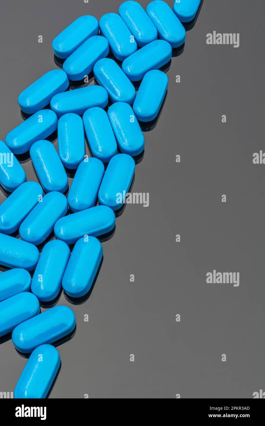 Blue pills on reflective dark background. For medicine, illness and