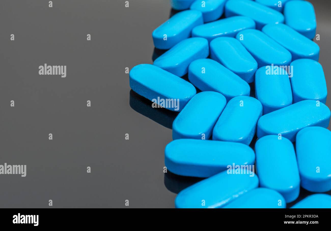 Blue pills on reflective dark background. For medicine, illness and