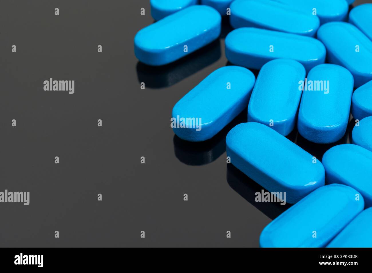 Blue pills on reflective dark background. For medicine, illness and ...