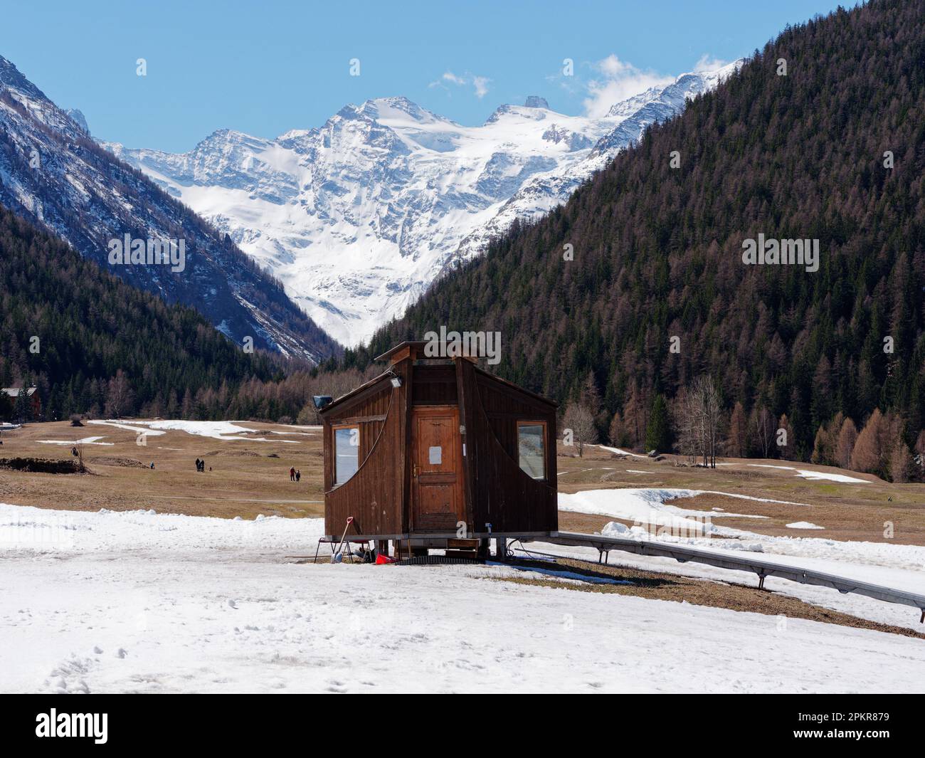 Wooden hut with mountain and forest behind in Cogne in springtime, Gran Paradiso National Park, Aosta Valley, Italy. Stock Photo