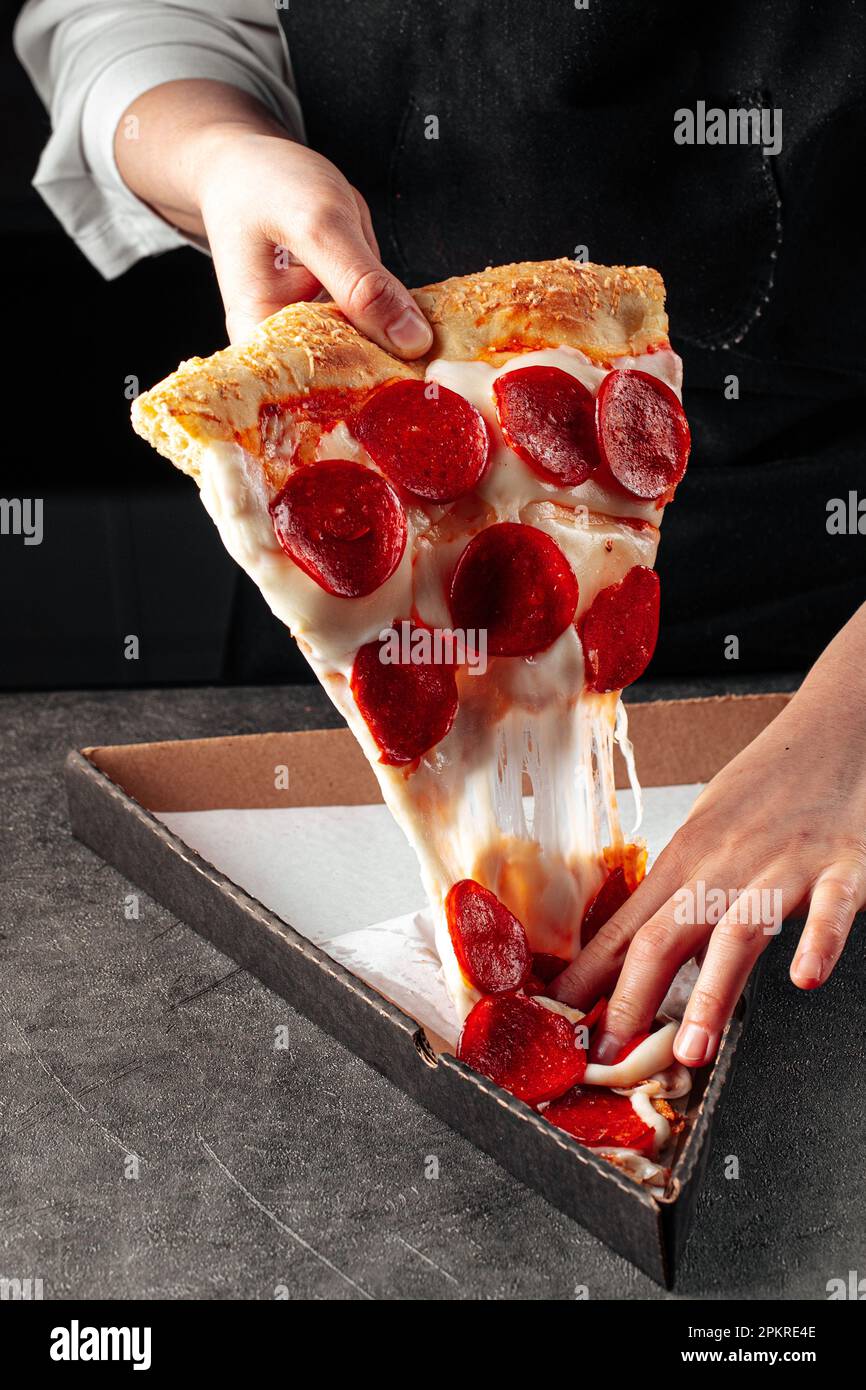 Baker tearing off a slice of pepperoni pizza Stock Photo Alamy
