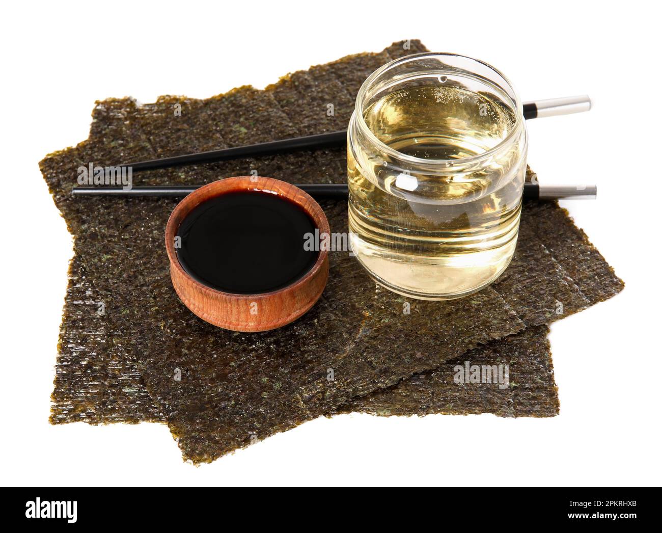 Glass of rice vinegar, soy sauce and nori sheets on white background