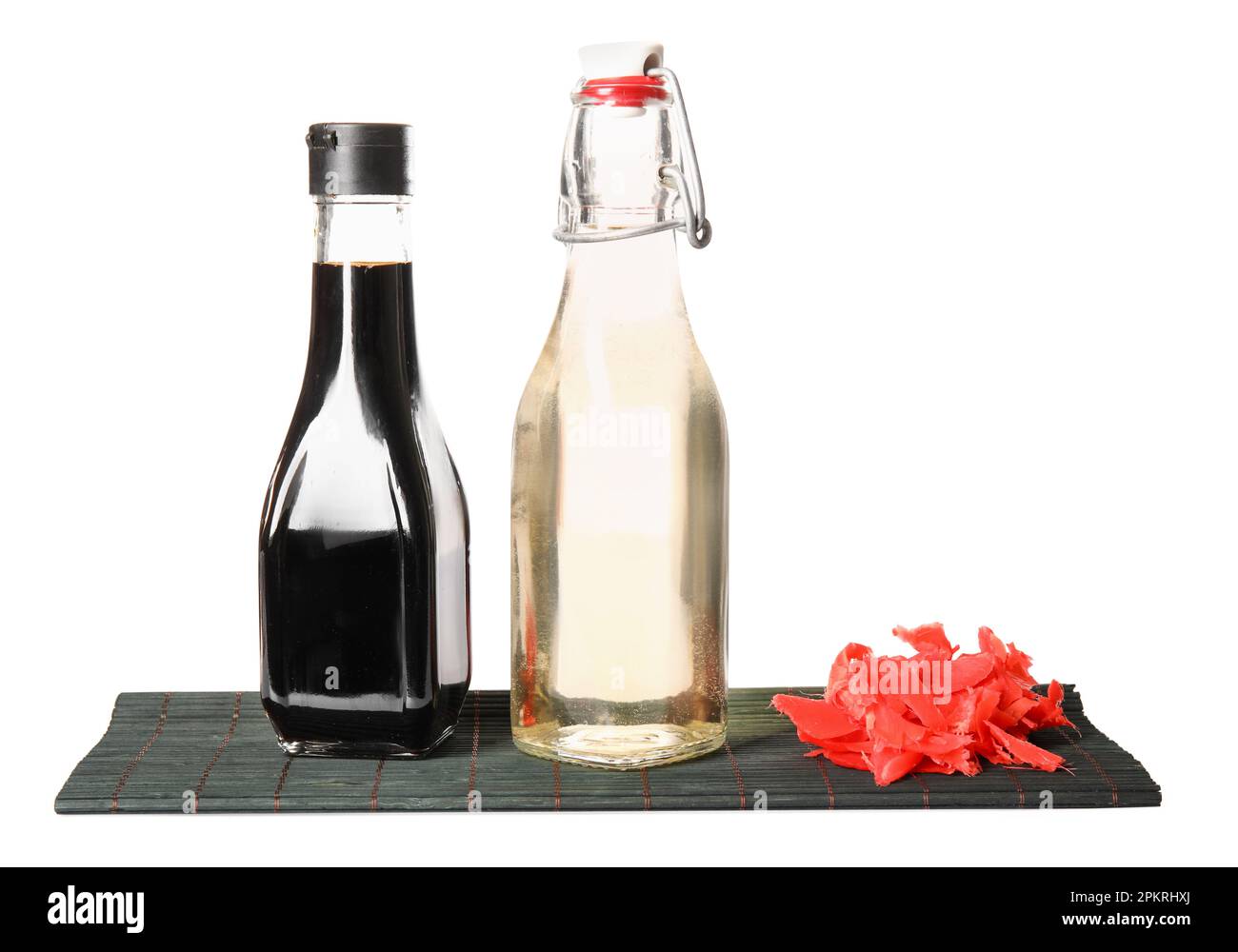 Bottles of rice vinegar, soy sauce, ginger and bamboo mat on white