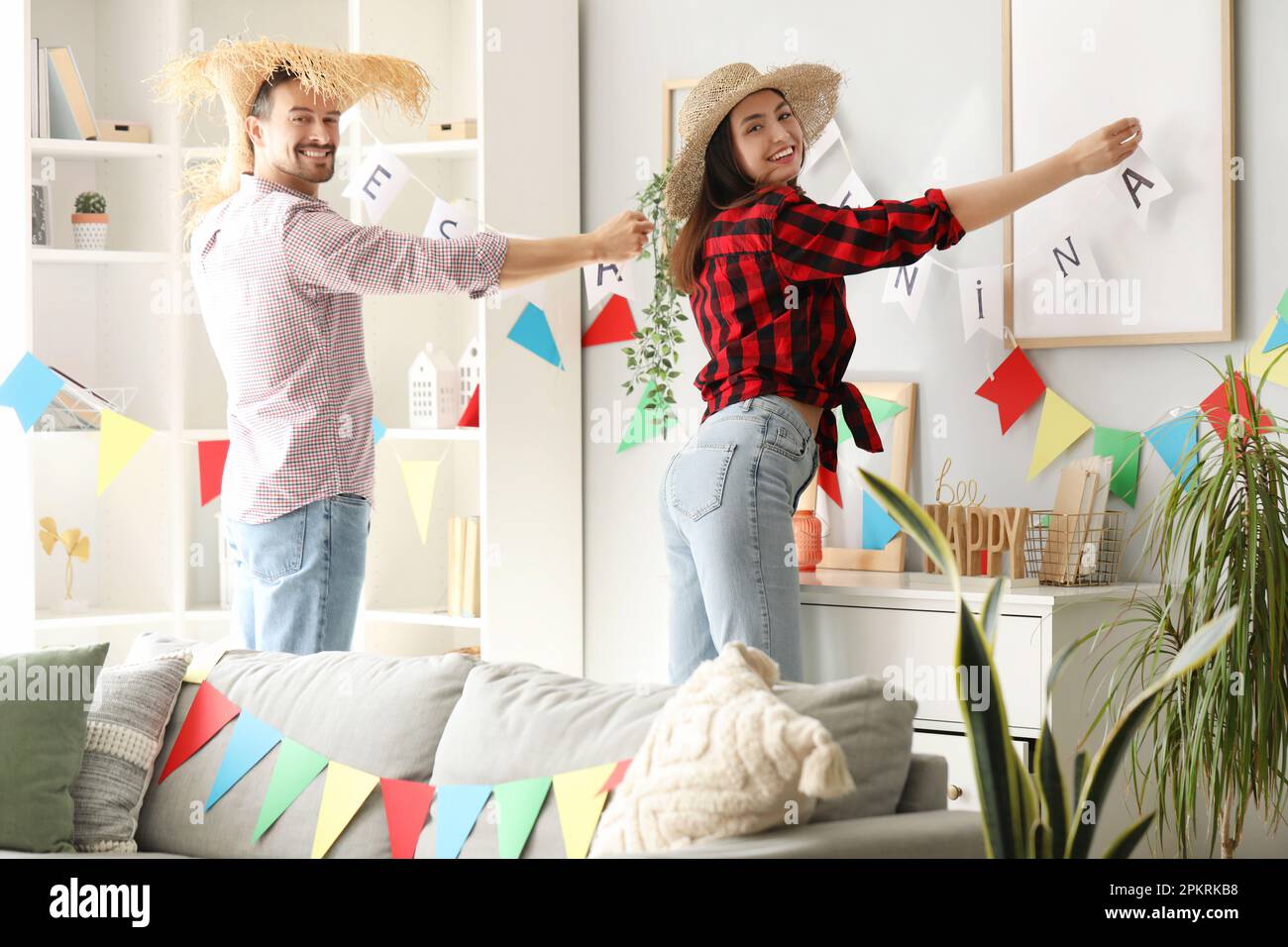 Young couple decorating wall with flags for Festa Junina (June Festival
