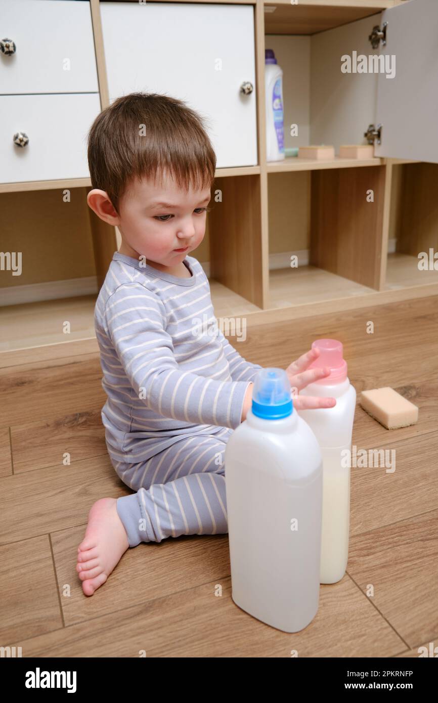 Toddler baby plays with household chemicals and detergent from the