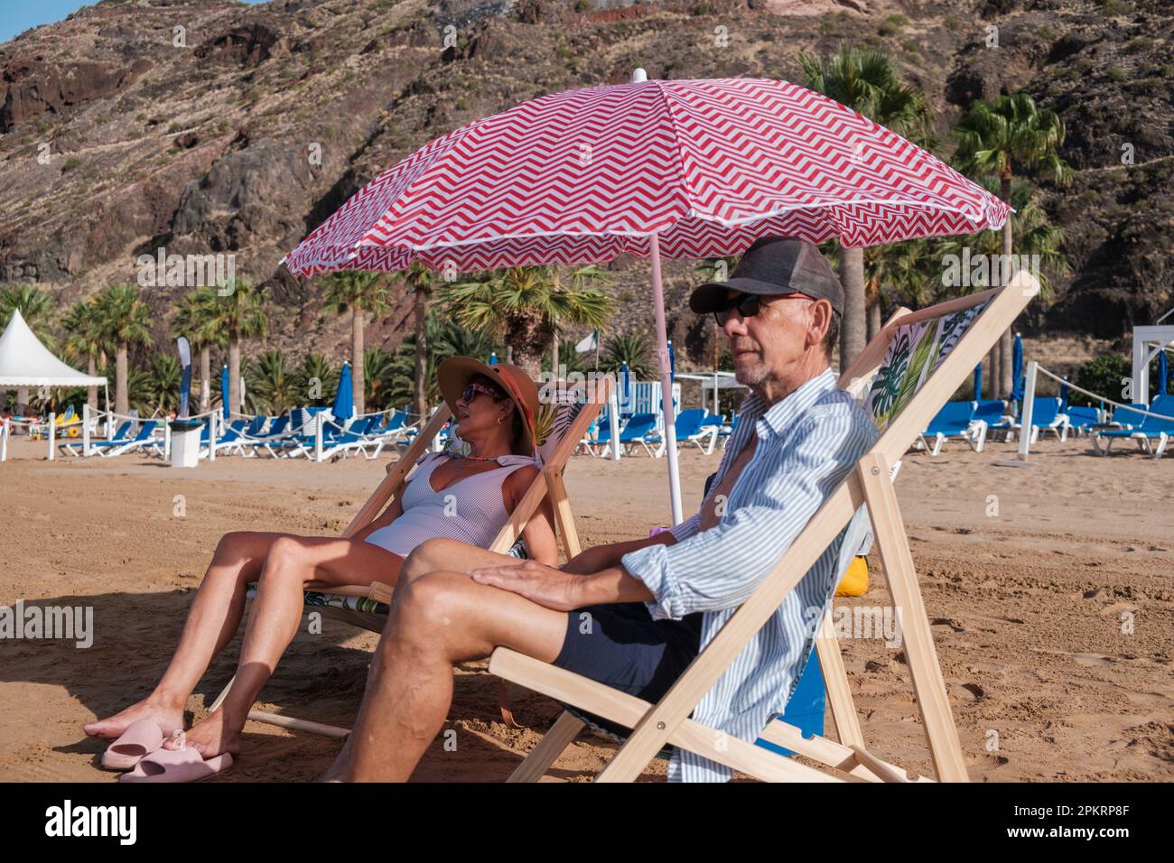 senior couple sitting on beach chairs and enjoying a day at the beach ...