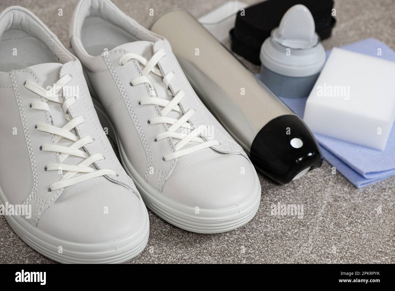 Applying a water-repellent hydrophobic spray to white women's sneakers.  Protection of shoes from moisture, dirt and unpleasant odor Stock Photo -  Alamy