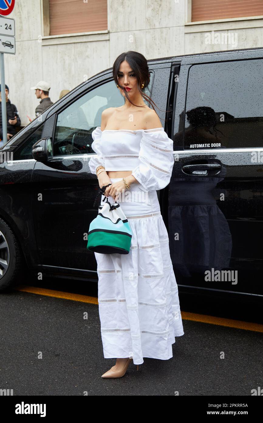 MILAN ITALY FEBRUARY 26 2023 Woman with white top skirt and striped bag before Luisa