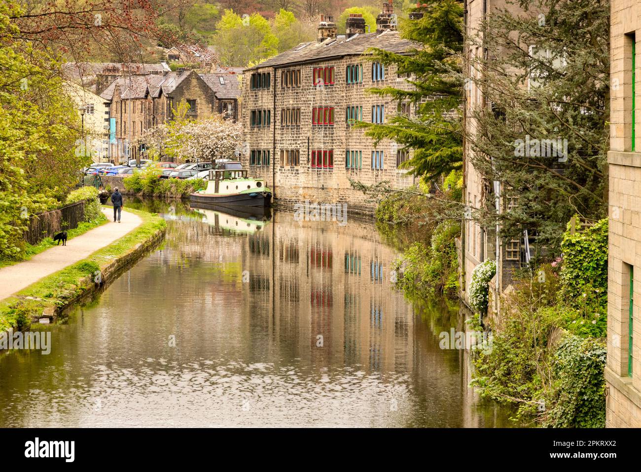 27 April 2022-Hebden Bridge, West Yorkshire, UK - A view along the canal at Hebden Bridge during spring. one person walking a dog on the tow path. Stock Photo