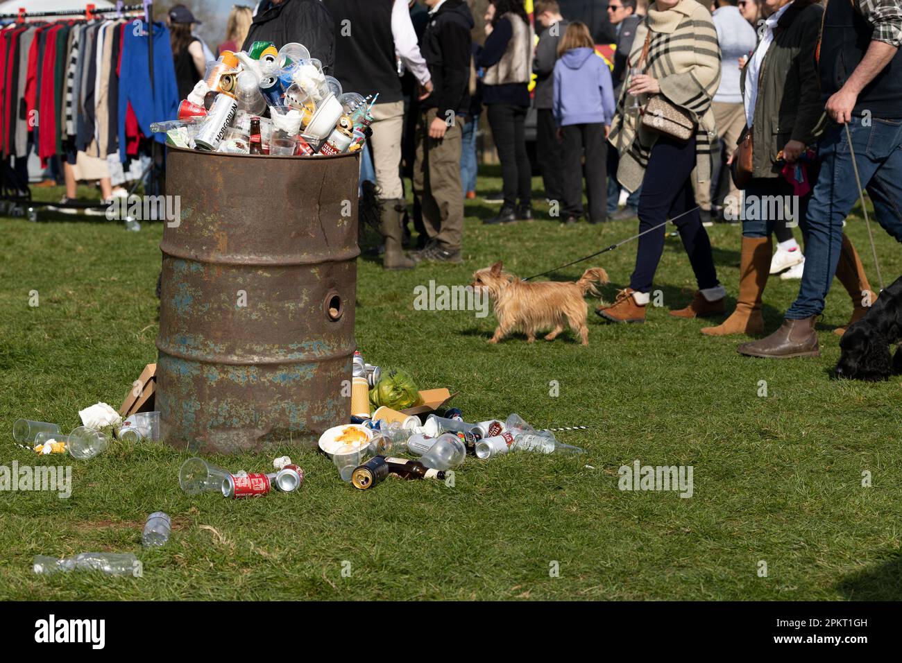 People walking passed an old drum bin at a country show, the rubbish