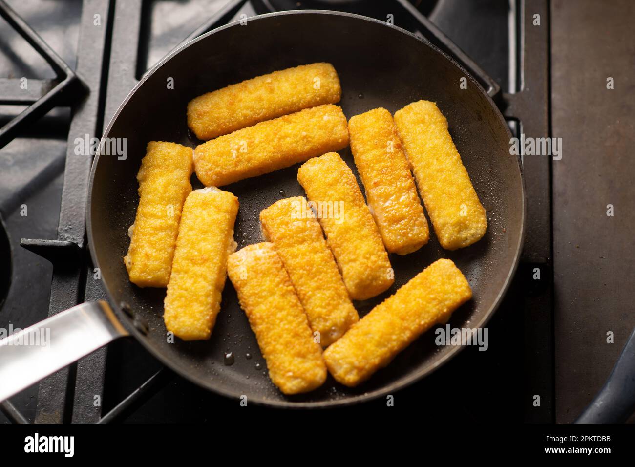 Breaded fish sticks in a frying pan. Preparation of frozen fish sticks