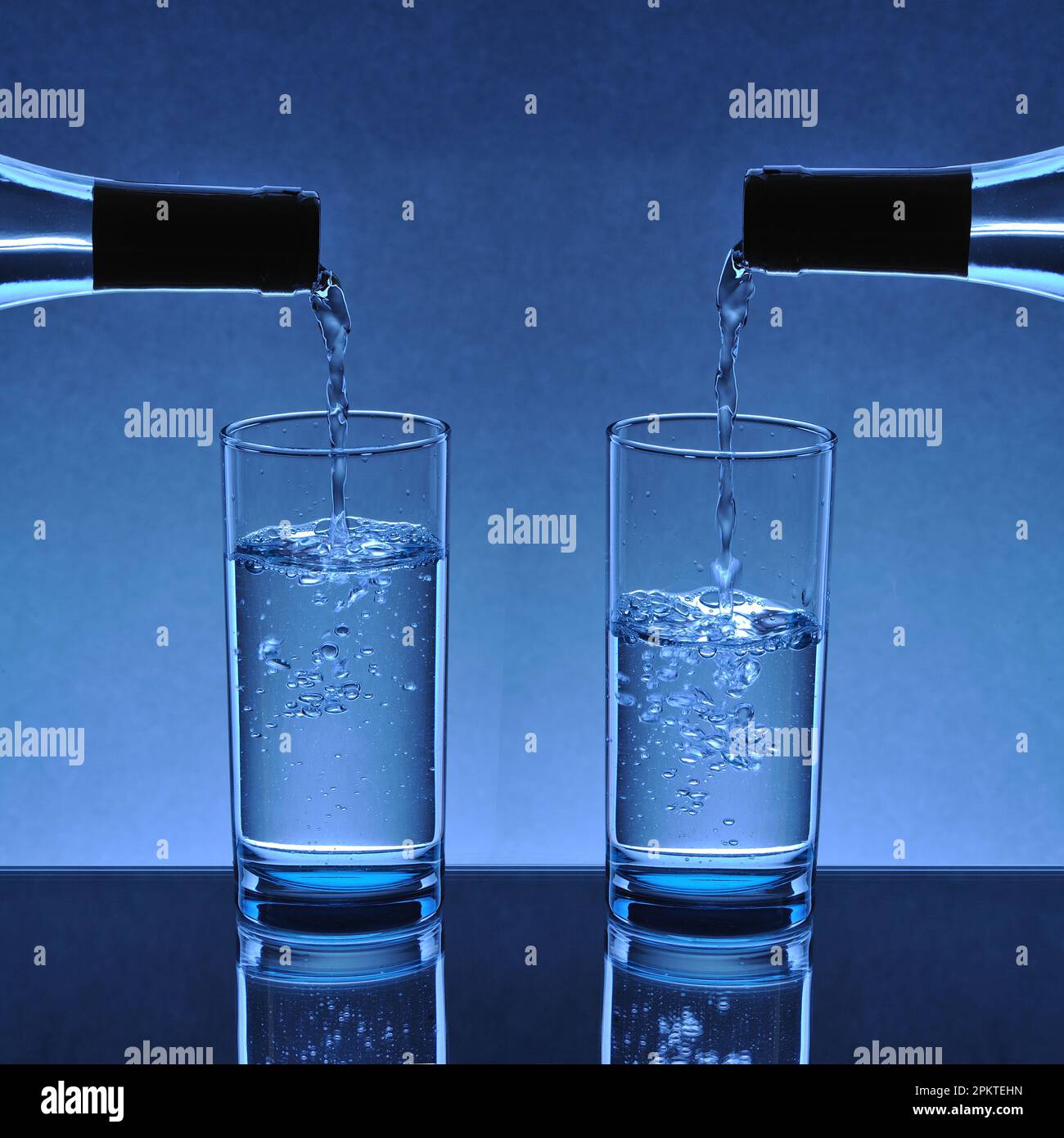 water glasses filling up with water flowing from the bottle mouth on a