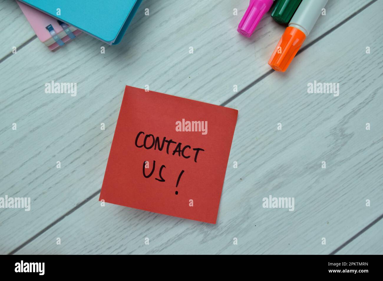 Concept of Contact Us! write on sticky notes isolated on Wooden Table. Stock Photo