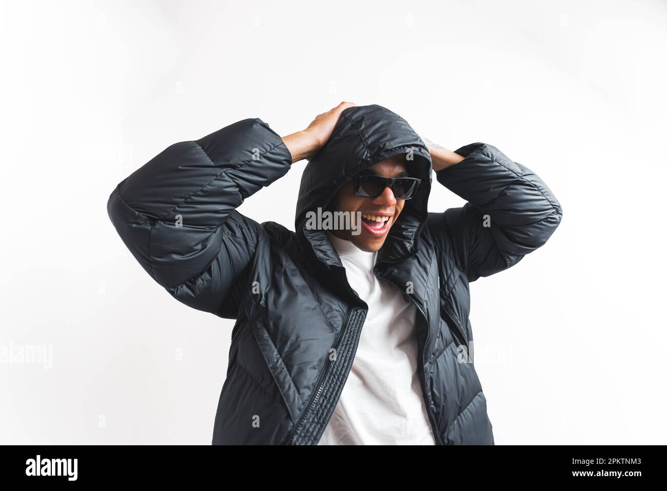 joyful young man wearing black sunglasses and a winter jacket, medium studio shot. High quality photo Stock Photo