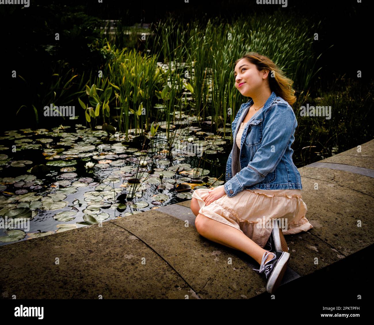 Attractive young woman wearing fancy universe print leggings sitting on a  bench in front of a small pond Stock Photo - Alamy