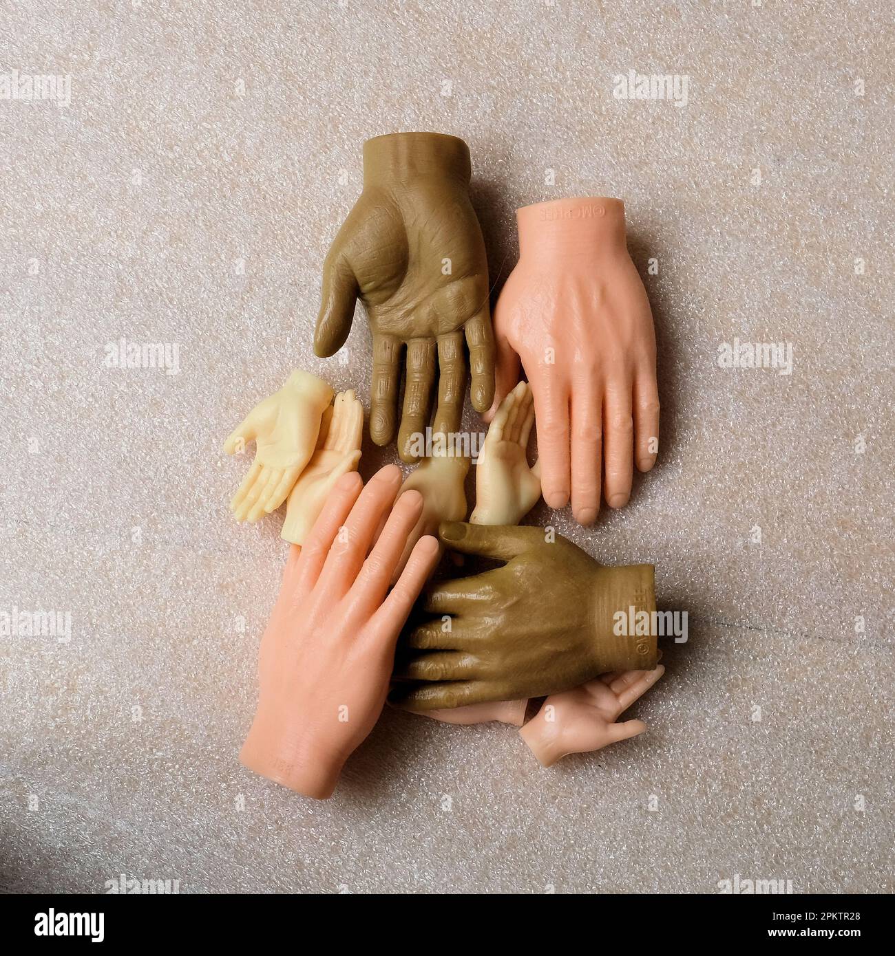 Plastic toy finger hands in different skin tones; help, assistance, harmony, diversity concept; tiny finger hands. Stock Photo