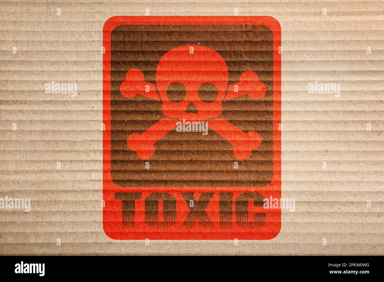 Hazard warning sign (skullandcrossbones symbol and word TOXIC) on cardboard, top view Stock