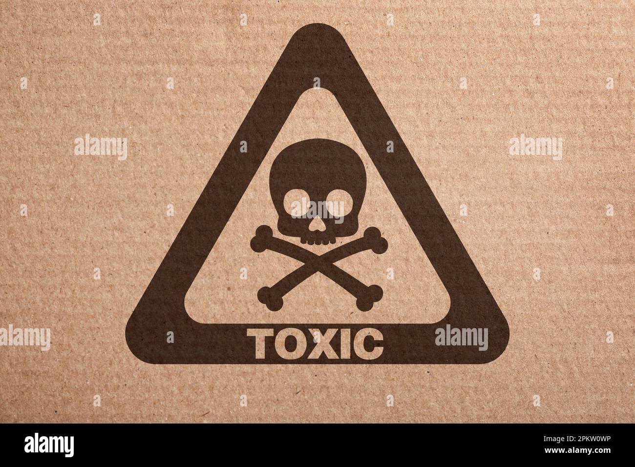 Hazard warning sign (skullandcrossbones symbol and word TOXIC) on cardboard, top view Stock
